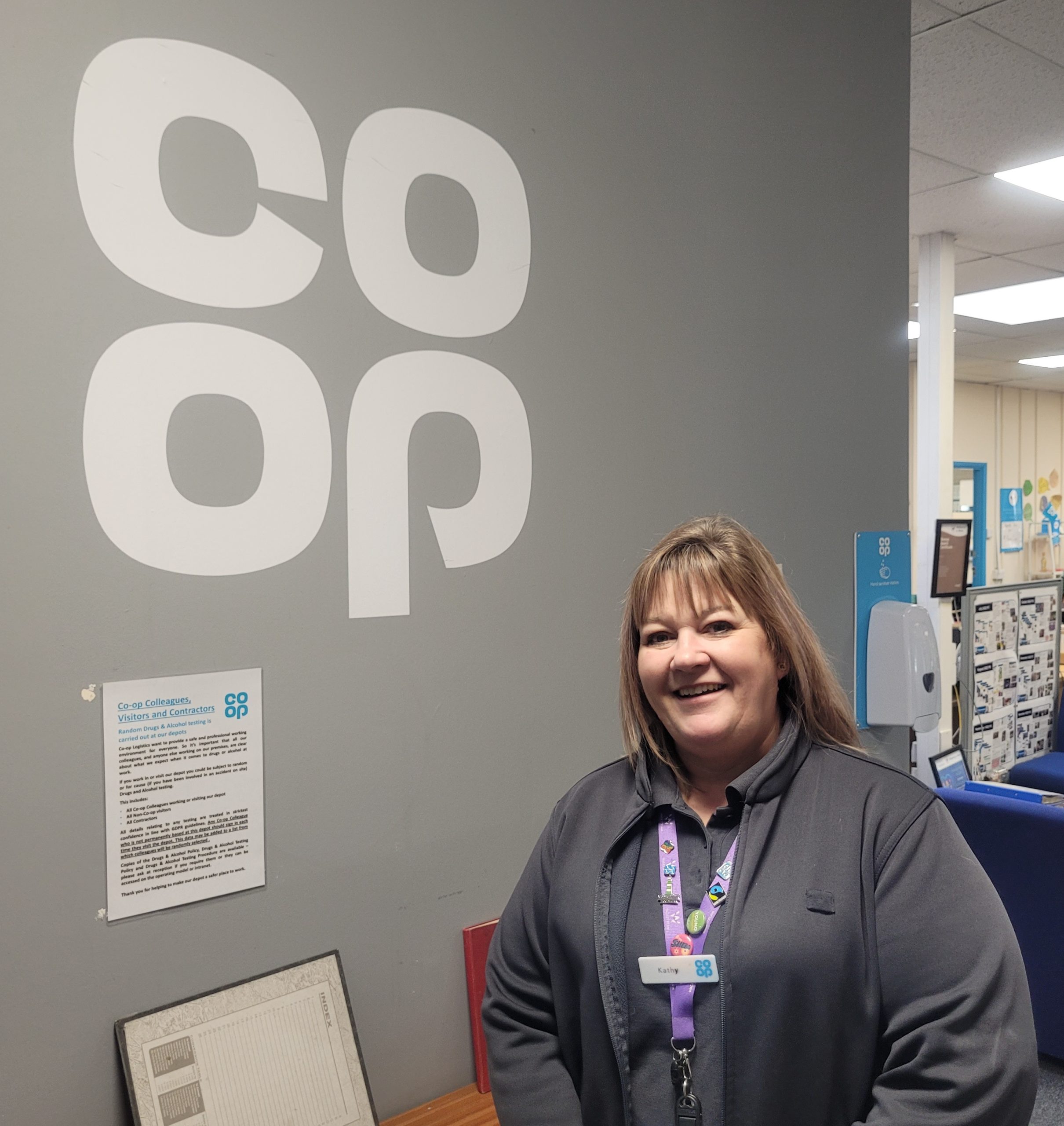 Katherine Hendrick standing next to Coop Logo