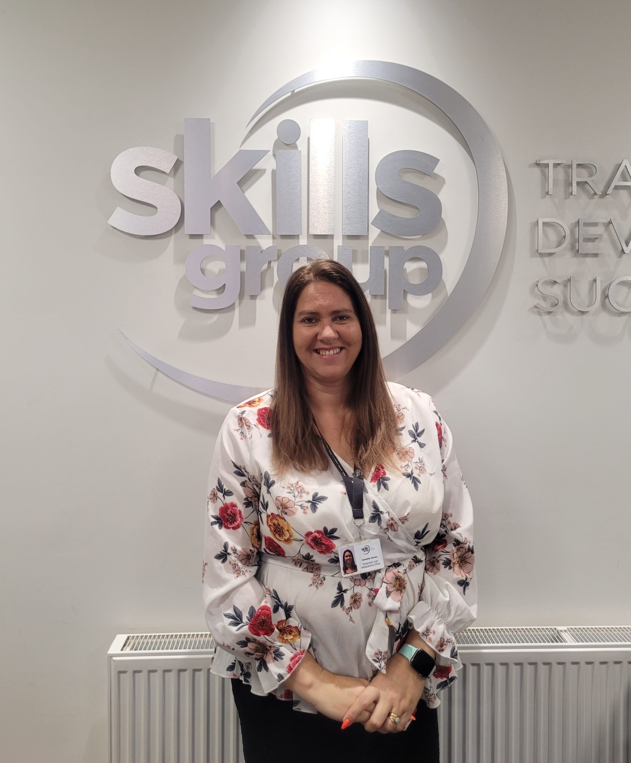 Annette Davey in front of Skills Group logo