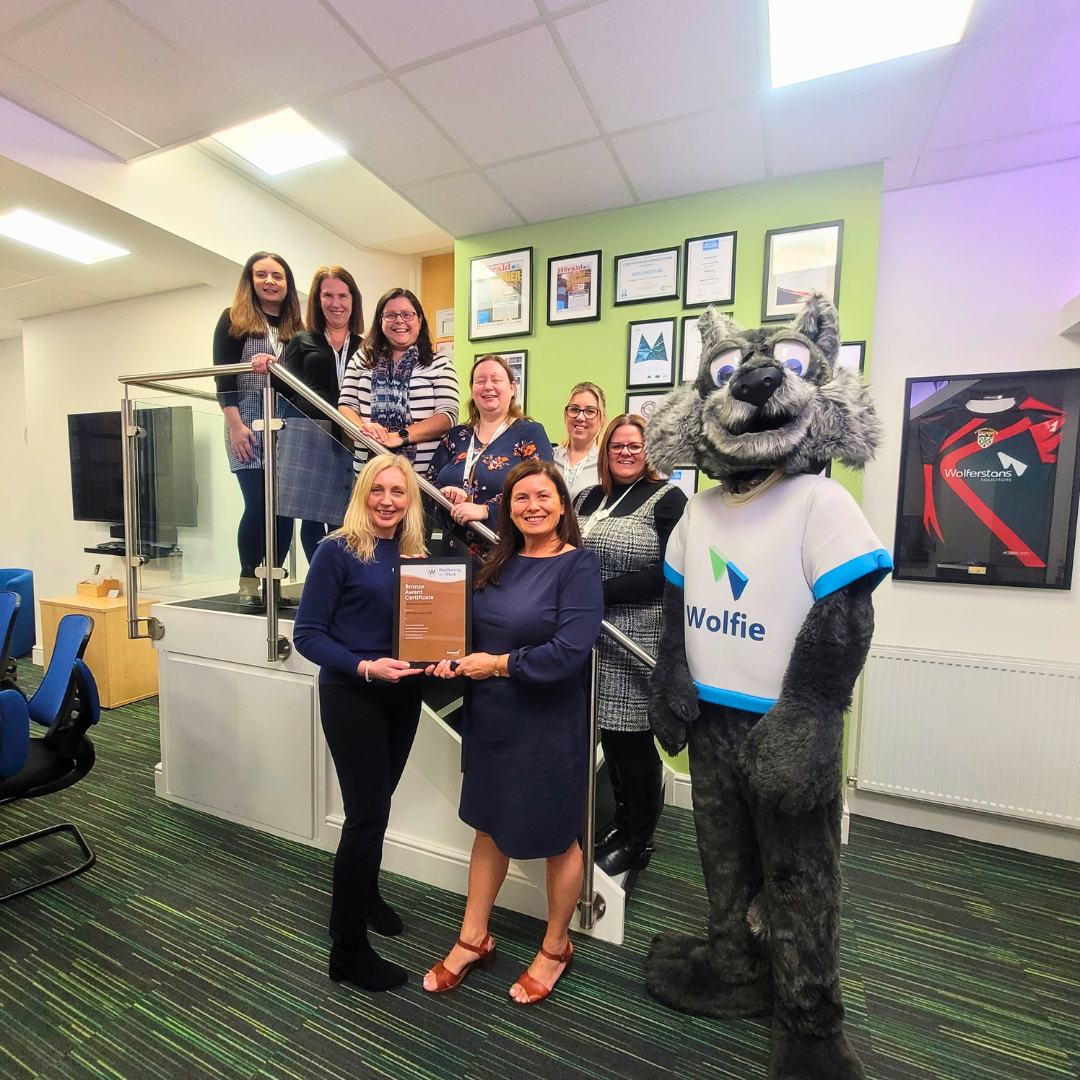 Group of individuals smiling with their award for wolferstans with their mascot Wolfie